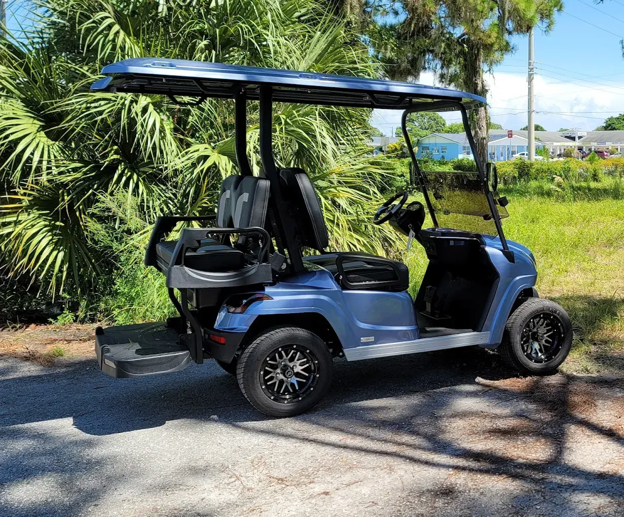 Several parked golf carts in a warehouse, including red, white, and blue carts with roofs.