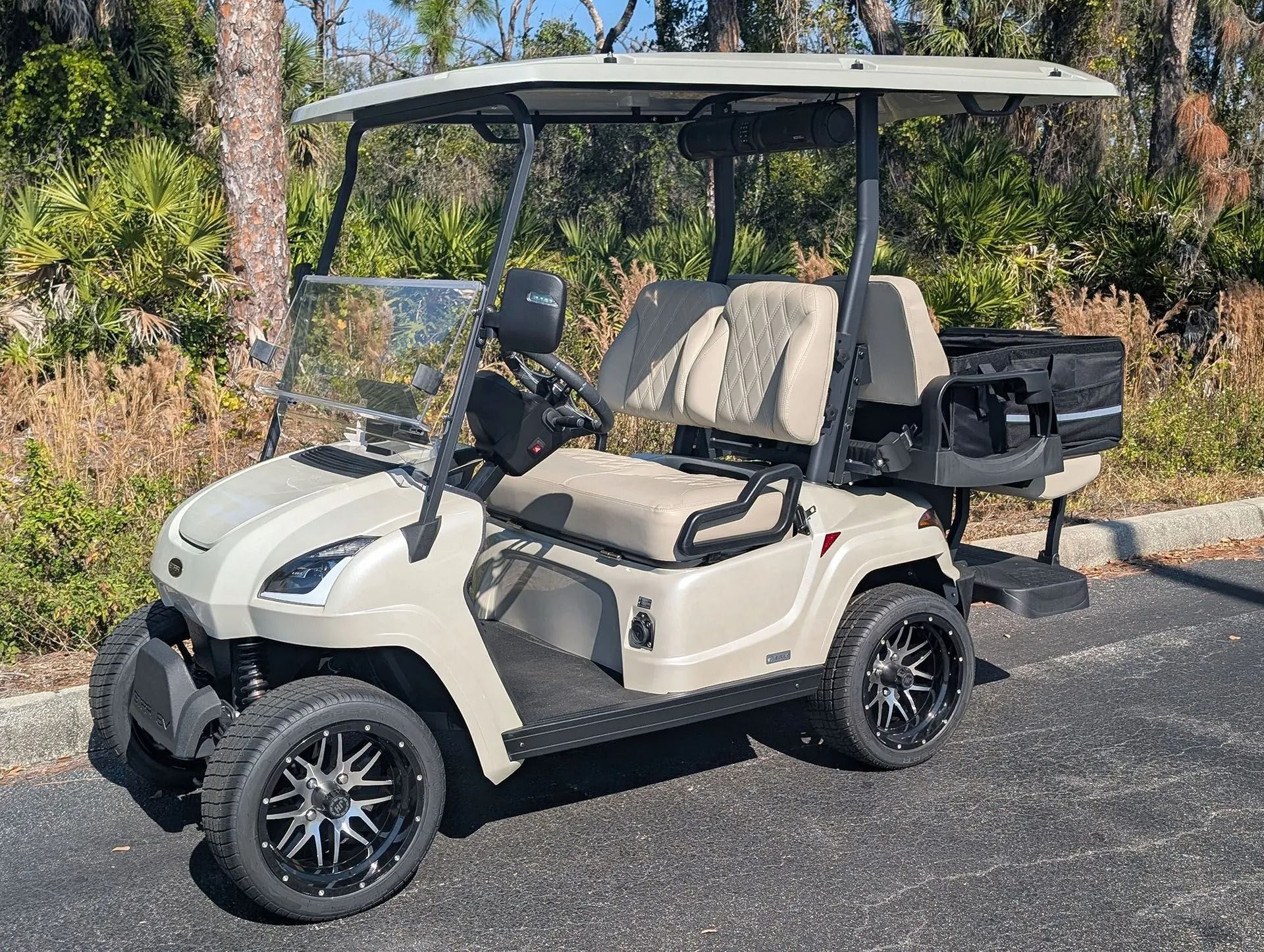 Gray golf cart with a black roof and mesh windshield parked outdoors in a lot