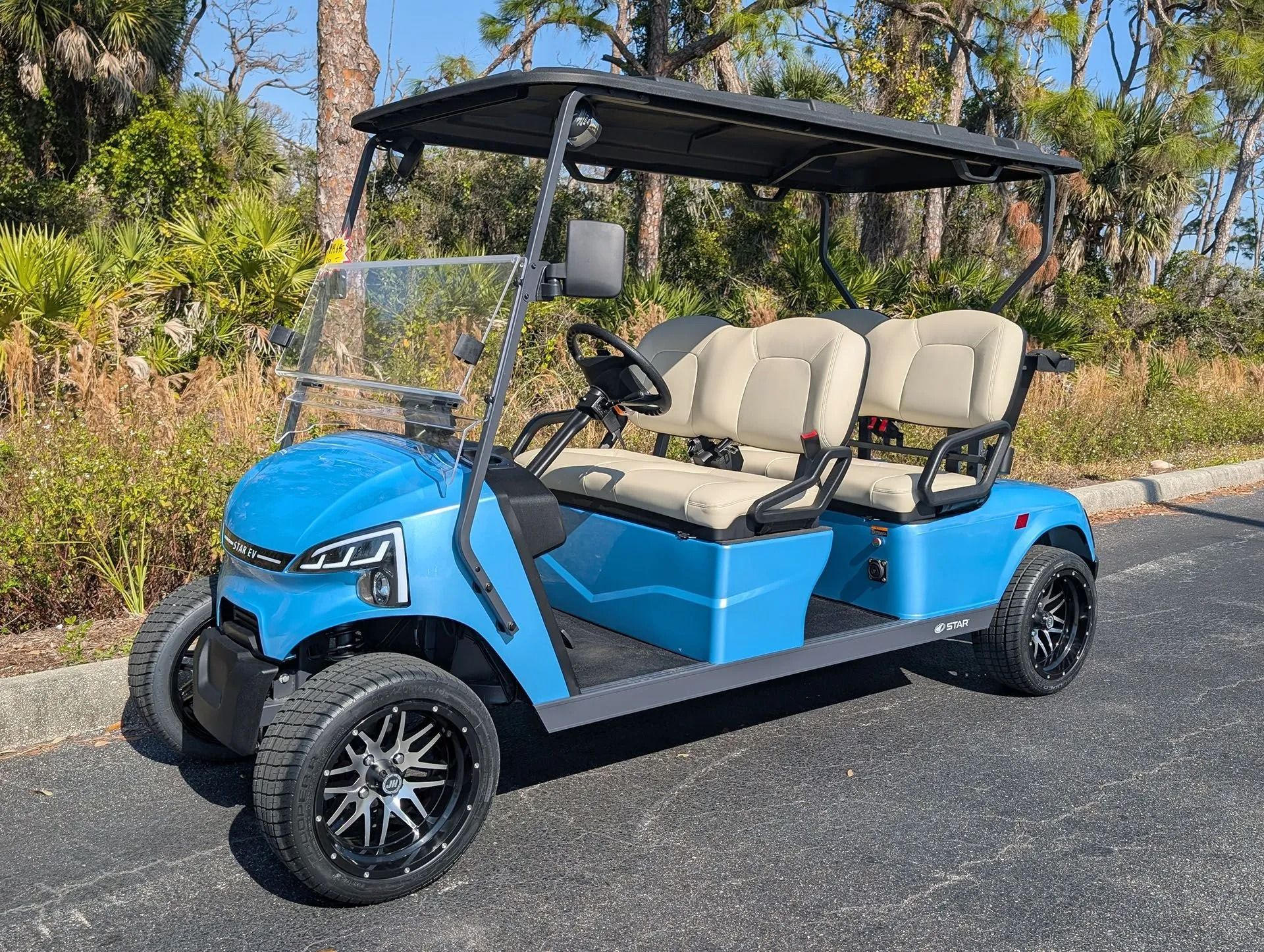 Turquoise golf cart with black seats parked among other golf carts indoors