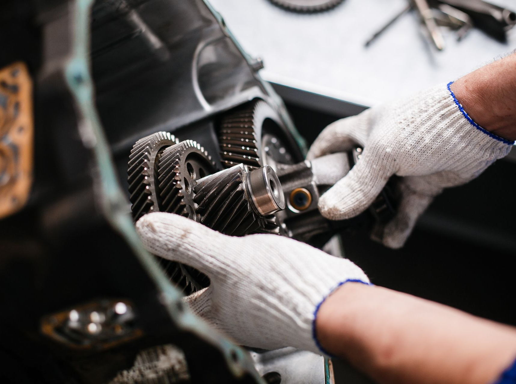 Gloved hands assembling transmission gears inside a vehicle gearbox.