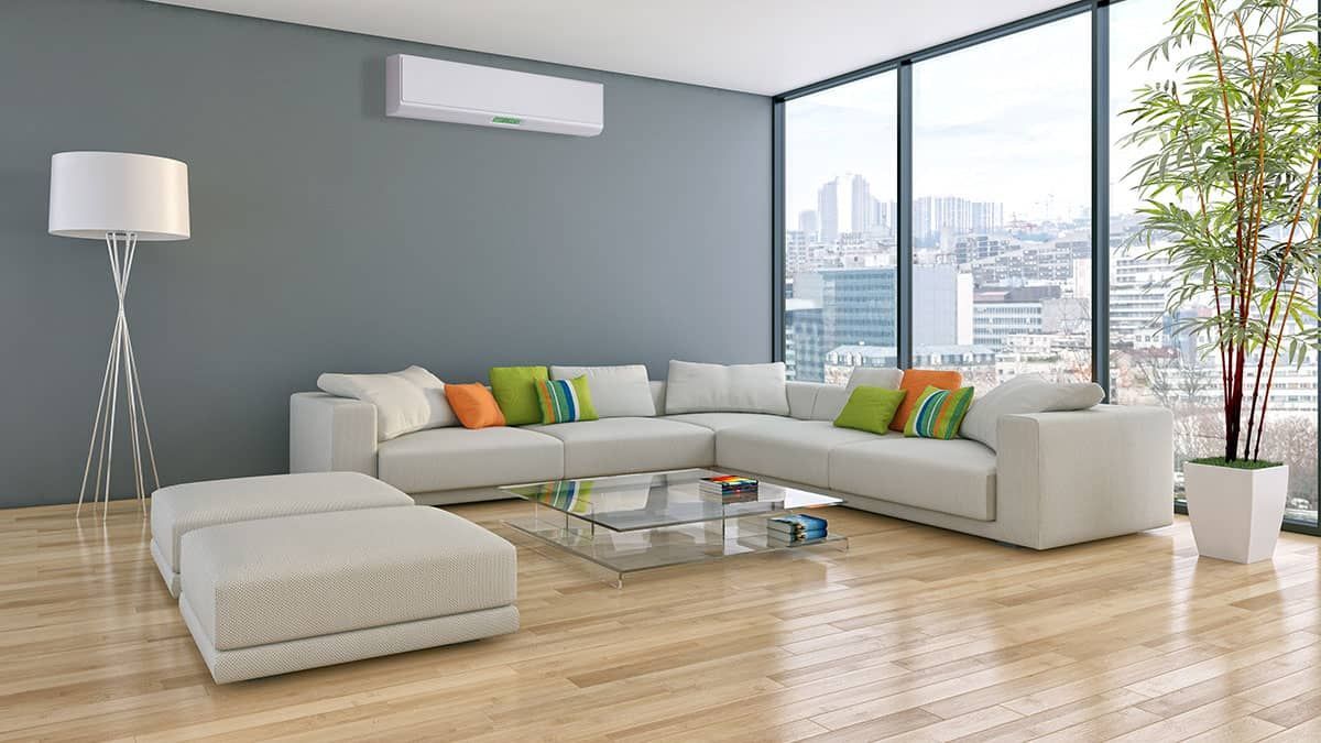 Modern living room with sectional sofa, large windows, and an air conditioner.