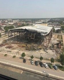 Aerial view of a partially demolished building with exposed steel beams and debris piles