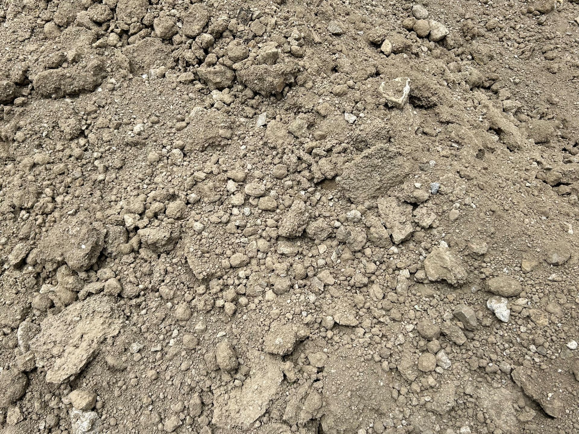 Pile of dry, clumpy soil; varying shades of brown and gray.