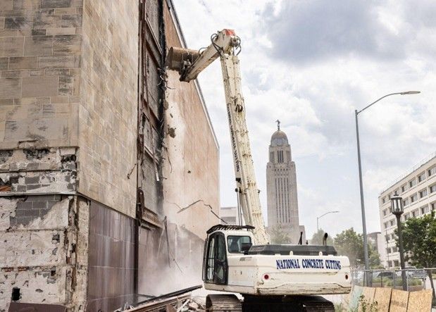 Building demolition contractors using heavy machinery to safely demolish a structure.