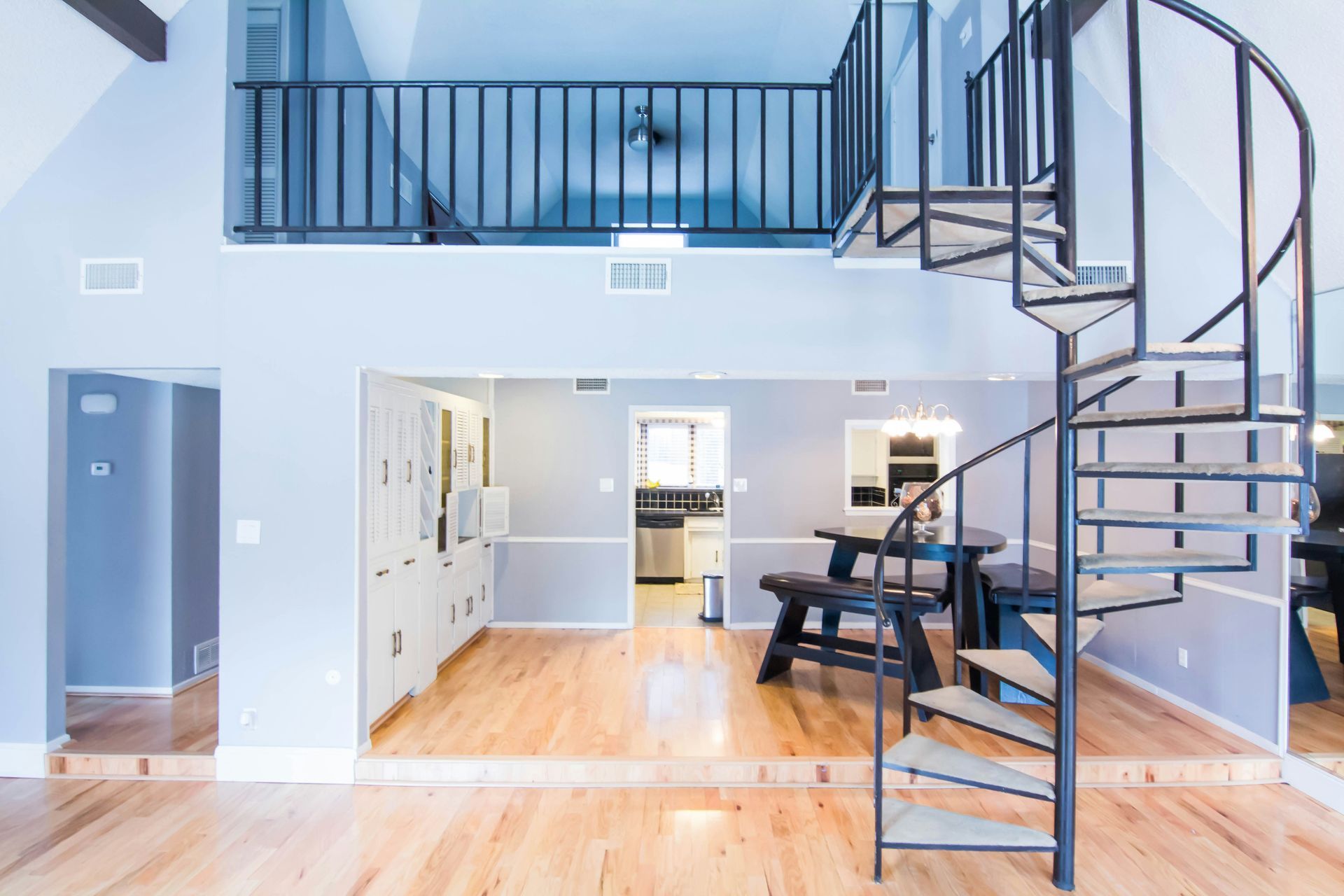 Modern loft interior with spiral staircase, loft railing, and open kitchen-dining area