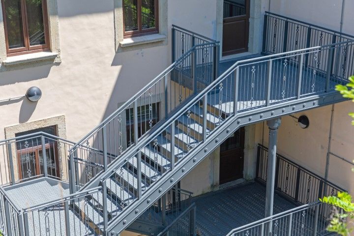 Exterior metal staircase on the side of a light-colored building.