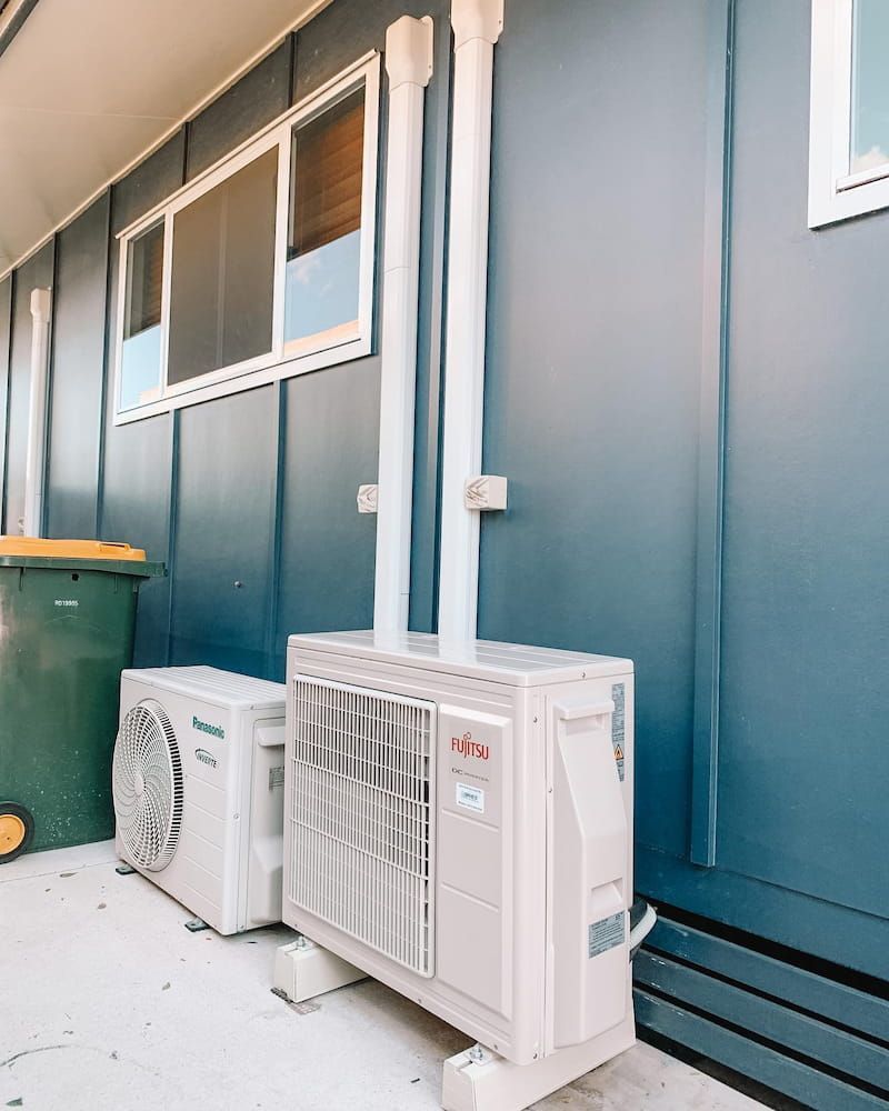 Two Air Conditioners Are Sitting on the Side of a Building — Davies Refrigeration & Air Conditioning in Warana, QLD