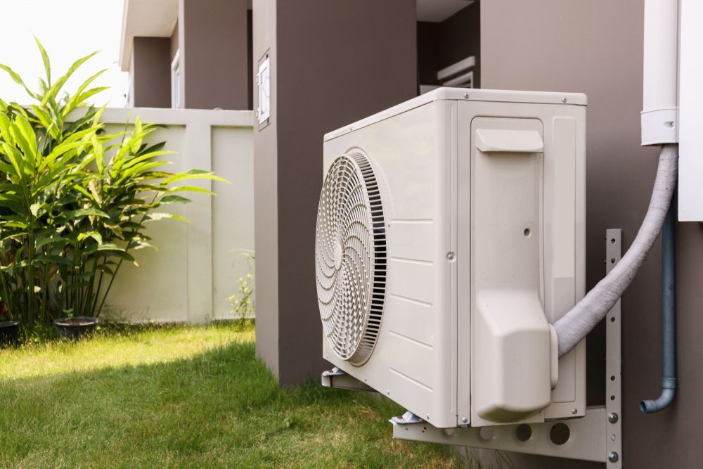 A White Air Conditioner is Mounted on the Side of a Building — Davies Refrigeration & Air Conditioning in Warana, QLD