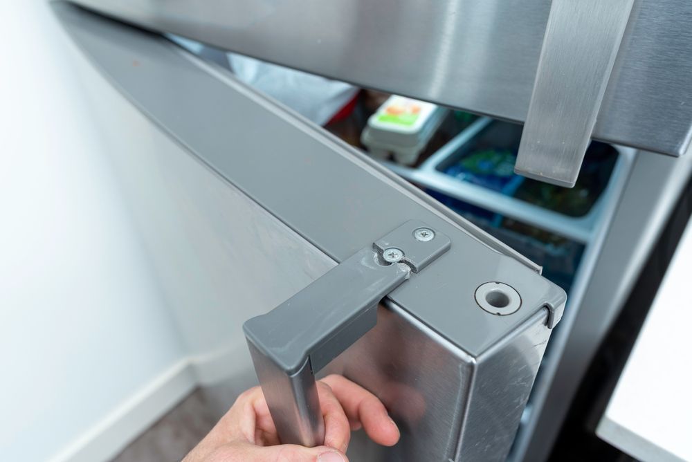 A Person is Opening a Stainless Steel Refrigerator Door — Davies Refrigeration & Air Conditioning in Warana, QLD