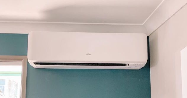 A White Air Conditioner is Hanging on a Blue Wall in a Room — Davies Refrigeration & Air Conditioning in Warana, QLD