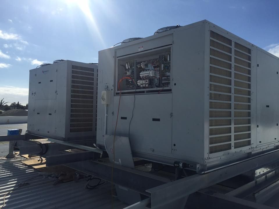 Two Air Conditioners Are Sitting on Top of a Metal Roof — Davies Refrigeration & Air Conditioning in Warana, QLD