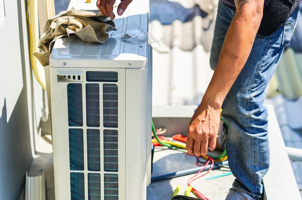 A Man is Working on an Air Conditioner Outside of a Building — Davies Refrigeration & Air Conditioning in Warana, QLD