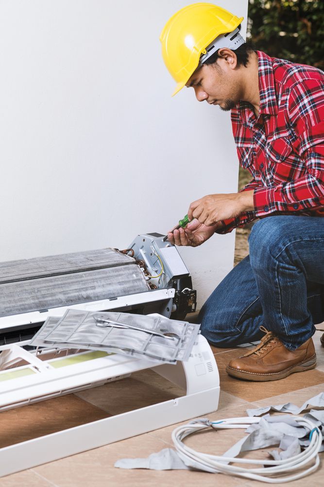 A Man Wearing a Hard Hat is Working on an Air Conditioner — Davies Refrigeration & Air Conditioning in Kawana, QLD