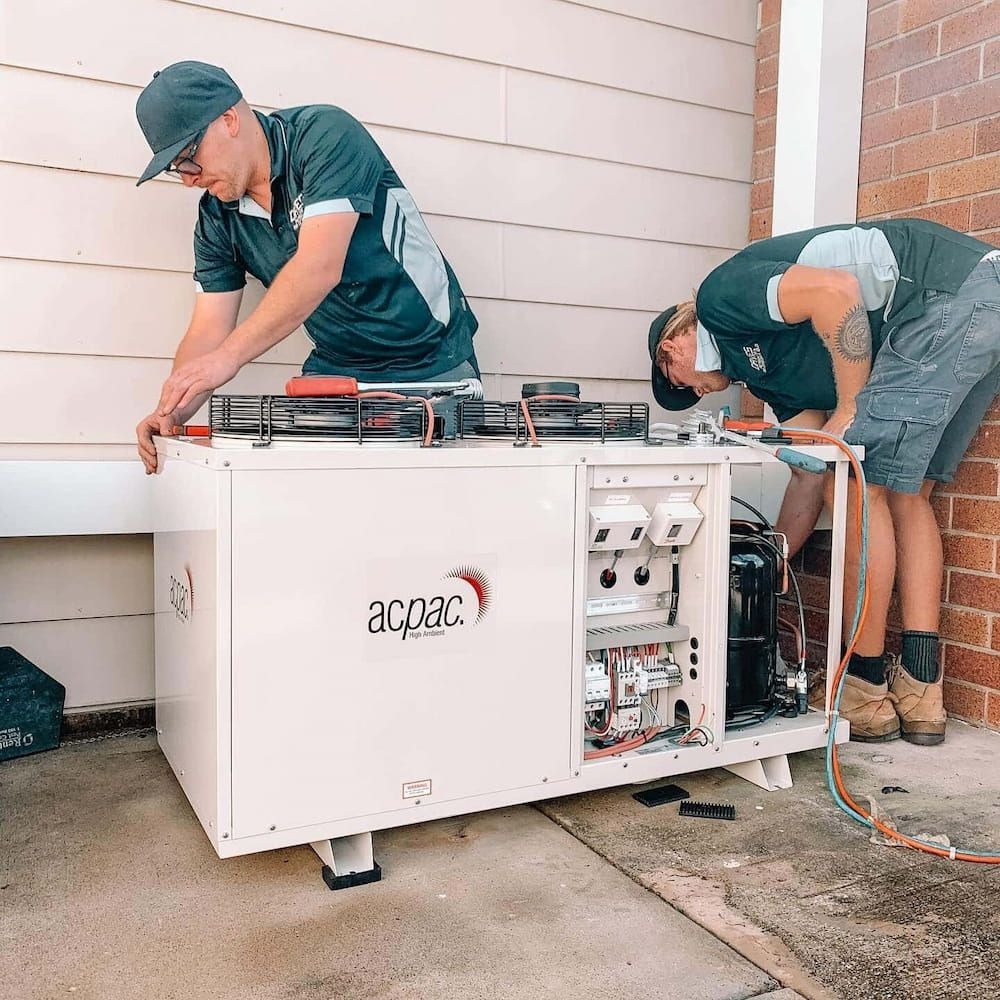 Two Men Are Working on a Machine That Says Acpac on It — Davies Refrigeration & Air Conditioning in Warana, QLD