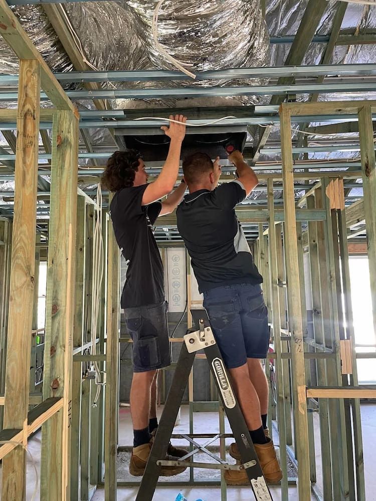 Two Men Are Working on a Ceiling in a Building — Davies Refrigeration & Air Conditioning in Warana, QLD