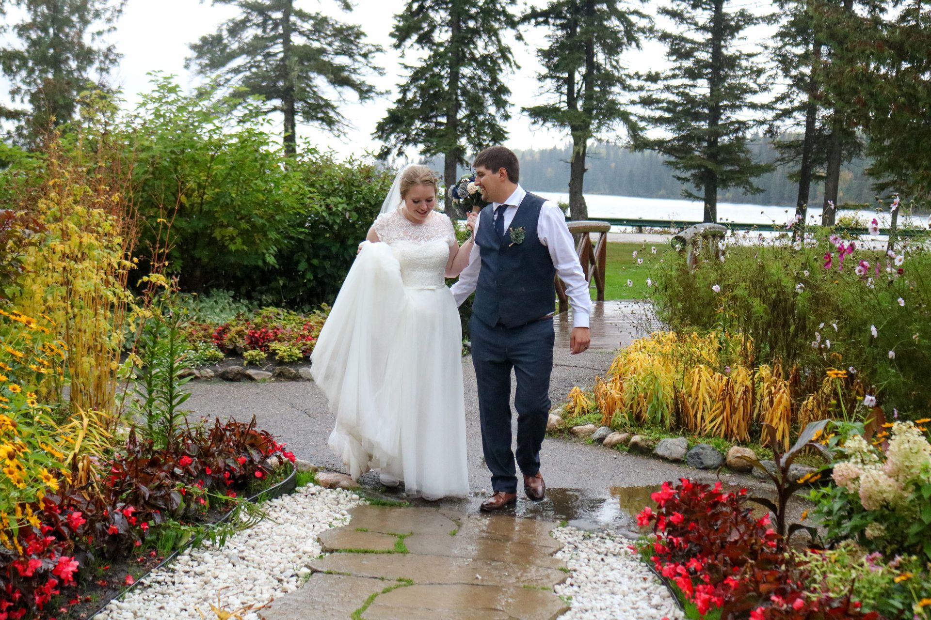Bride and groom walking together on a garden path amid colorful flowers and trees