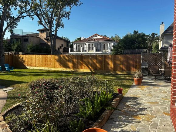 Black pipe partially buried in dirt, near a grave site with green grass and trees.