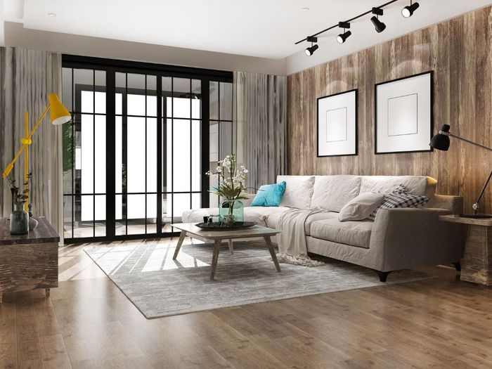 Living room with a sofa, coffee table, and wood-paneled accent wall; glass doors and windows.