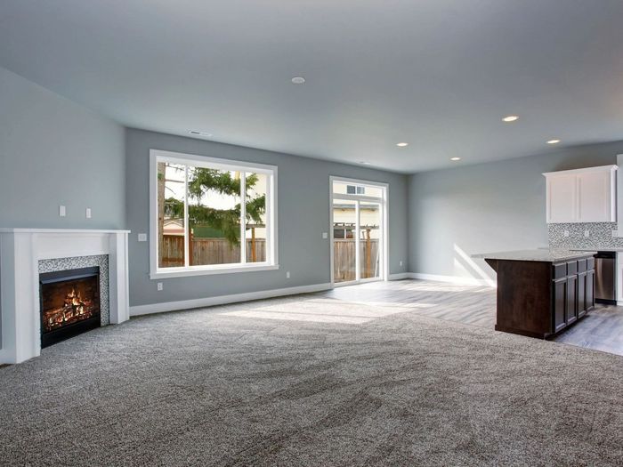 Spacious living room with gray carpet, fireplace, large window, and kitchen island.