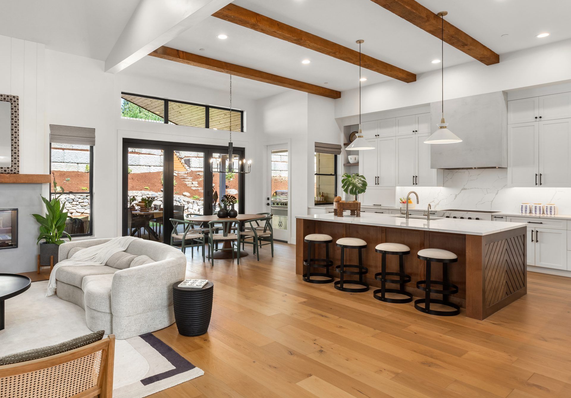 Open-concept kitchen and living area with hardwood floors, white cabinets, and a wooden island with bar stools.