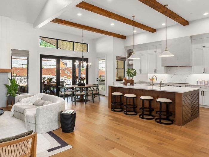 Spacious, open-concept kitchen and living area with wood floors, white cabinetry, and a large island with bar stools.