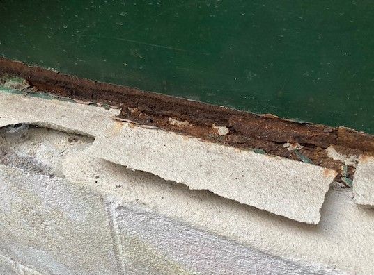 A close up of a piece of rusty metal on a brick wall.
