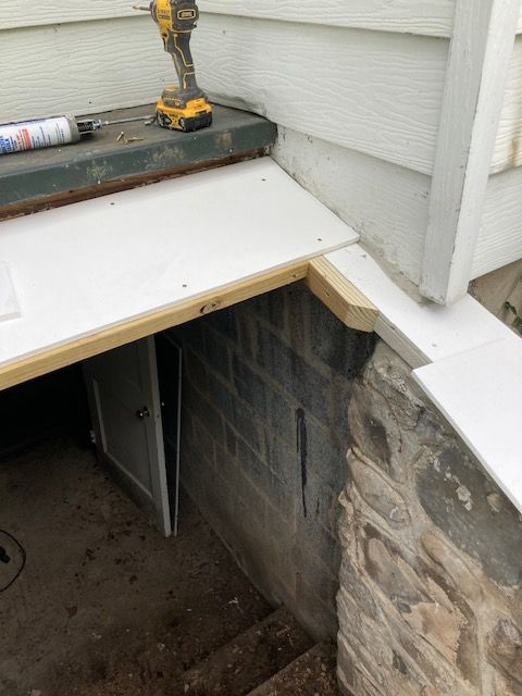 A drill is sitting on top of a wooden table next to a brick wall.