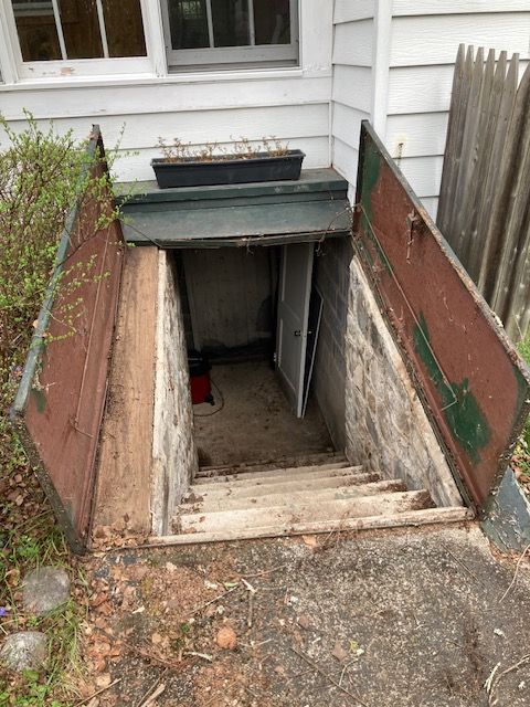A basement with stairs leading up to it and a door open.