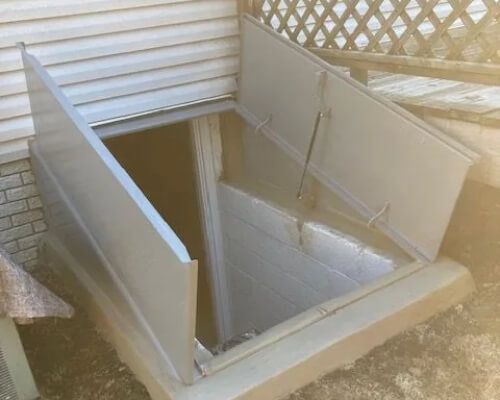 A basement door with the door open and stairs leading up to it.