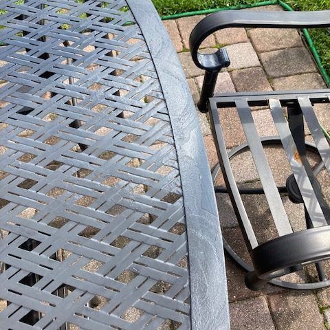 A metal table and chair are sitting on a brick patio.