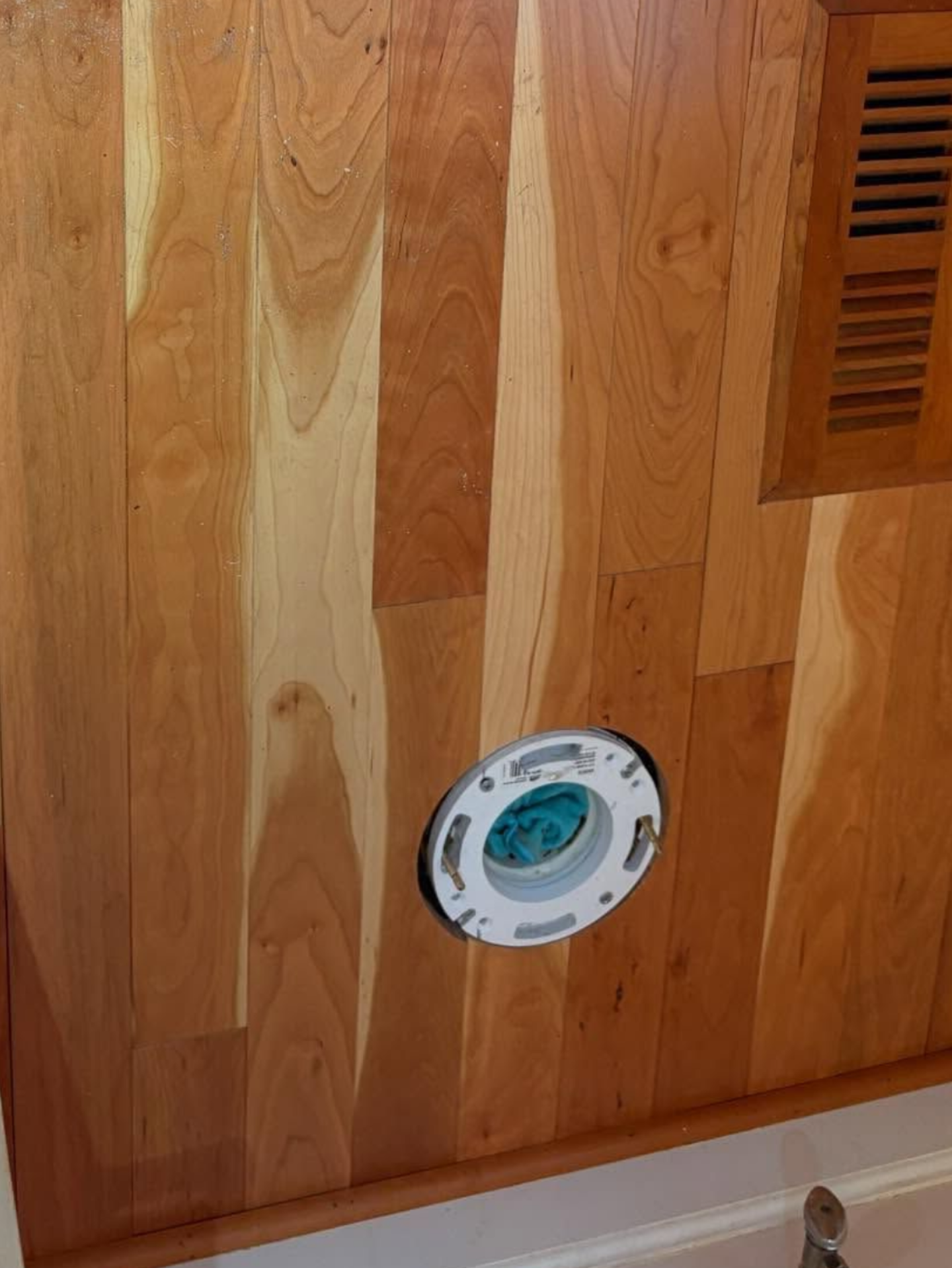 Wooden wall panel with a round thermostat and a small vent on the right