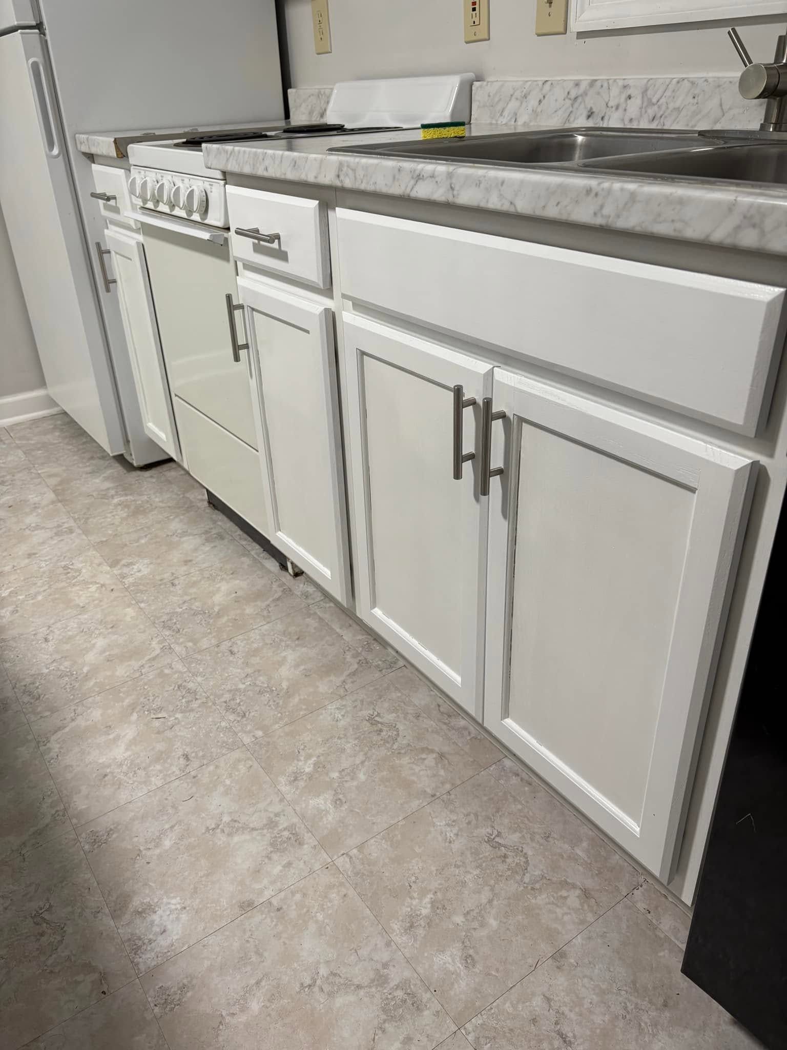 White kitchen cabinets with gray countertop and white refrigerator in a laundry or utility room