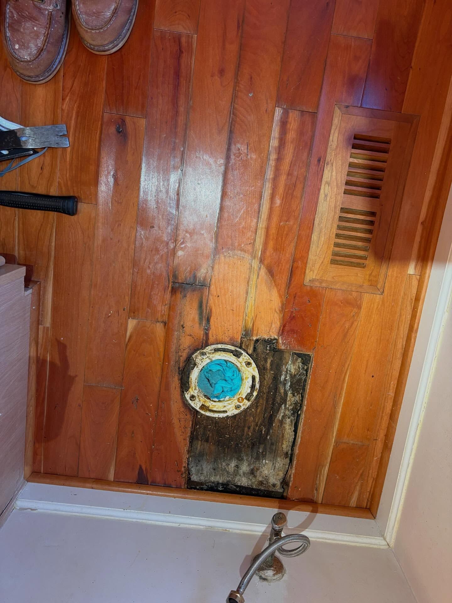 Close-up of a wooden door with a round lock and small vent grille near the bottom.