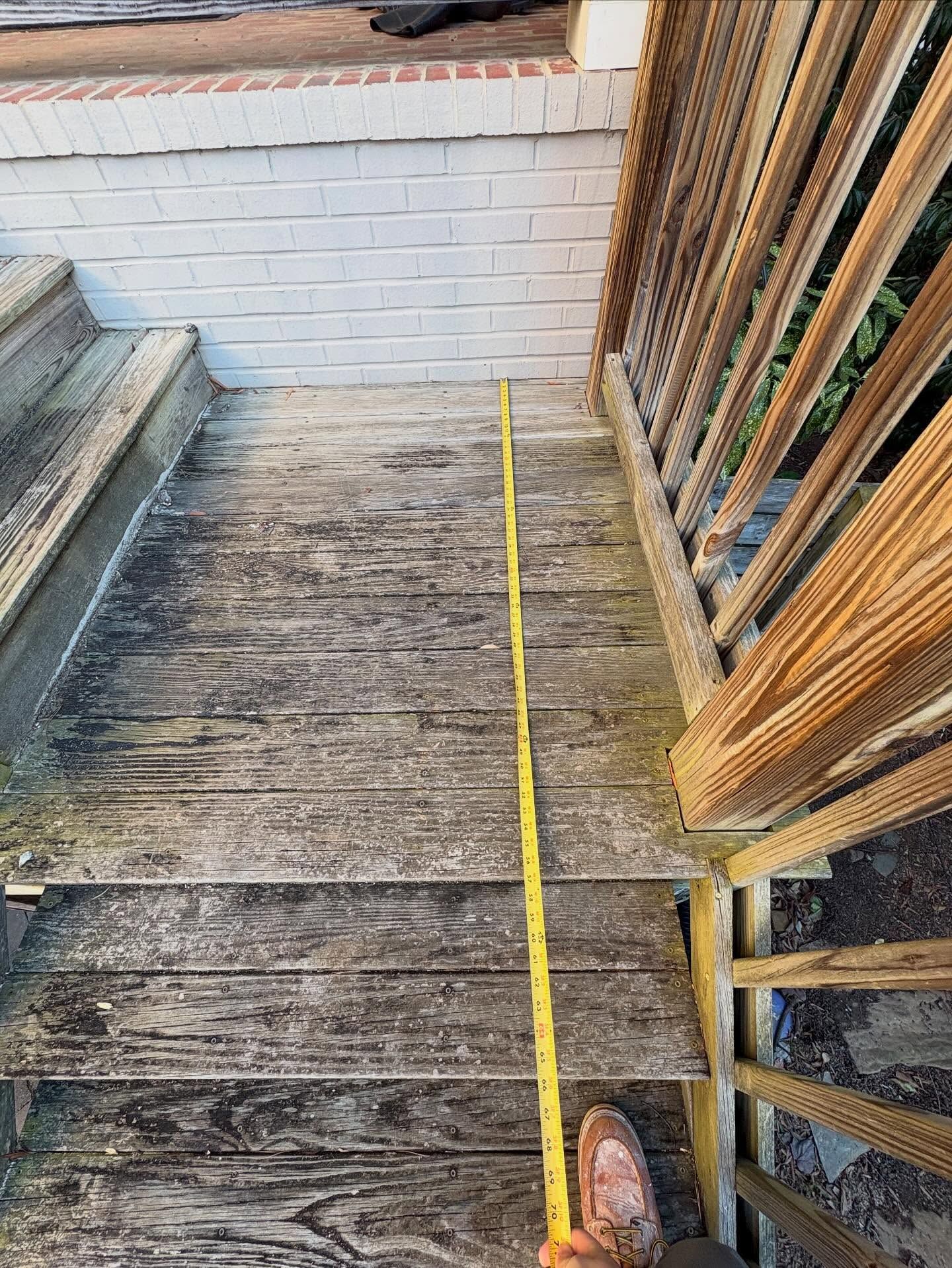 Wooden outdoor stairs with a yellow measuring tape running down the center beside a railing.