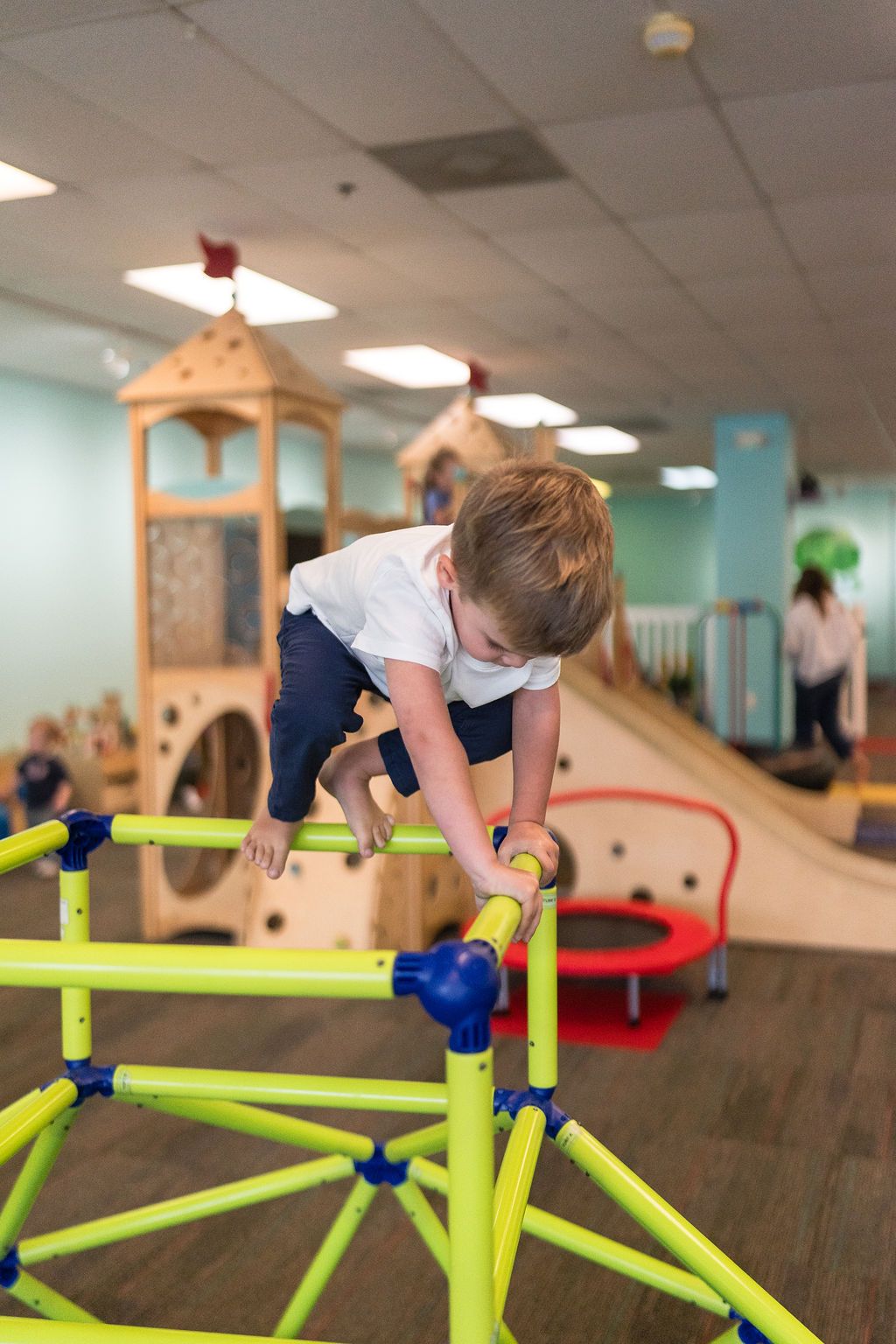 Child climbing on colorful indoor playground equipment in a playroom