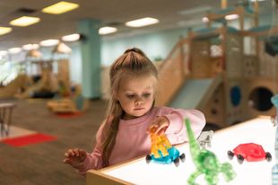Child playing with colorful toys at a table in an indoor play area
