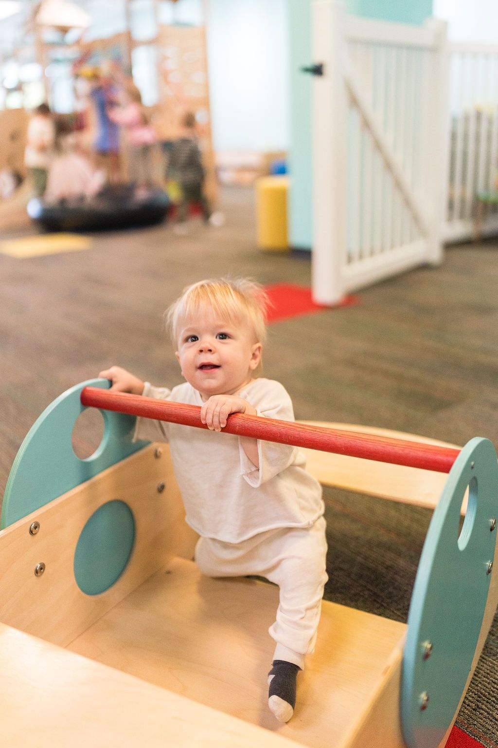 Toddler climbing on a wooden play structure in an indoor play area