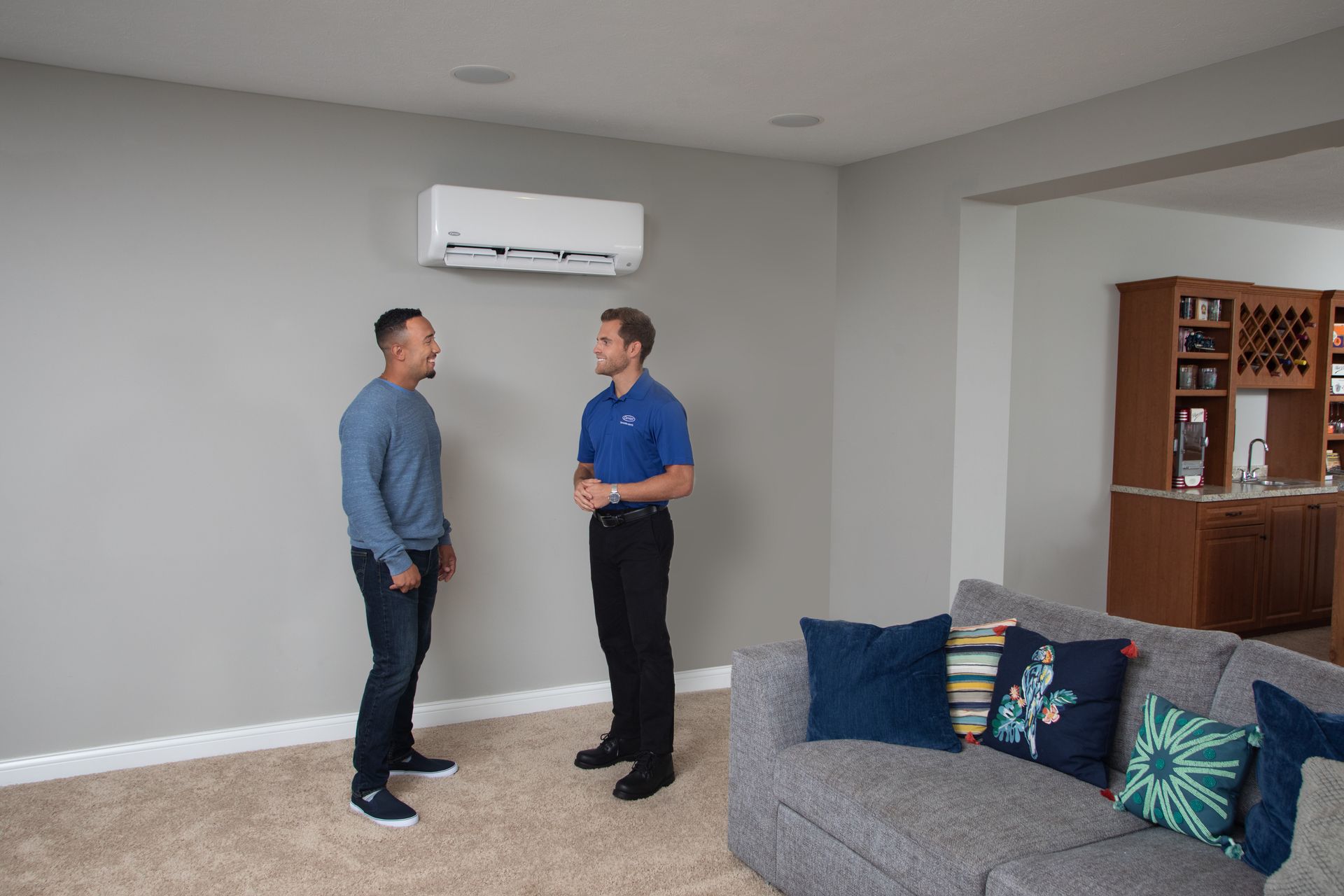 Two men are standing in a living room talking to each other.