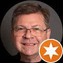 A man with glasses and a star in an orange circle.