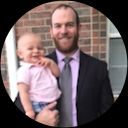 A man in a suit and tie is holding a baby in his arms.