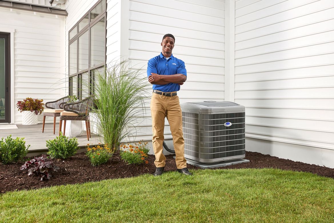 A man is standing in front of a house next to an air conditioner.