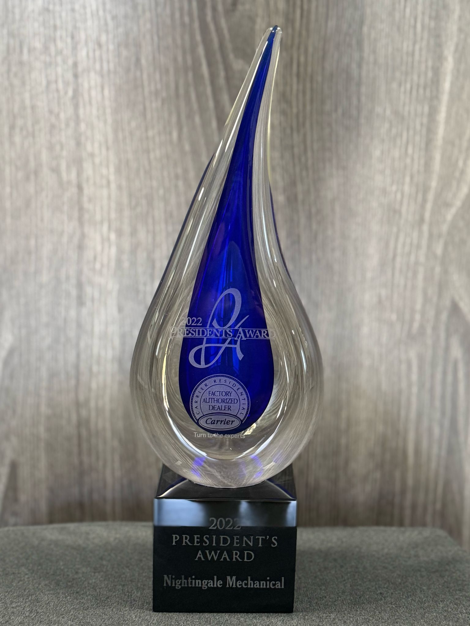 A blue glass trophy is sitting on top of a wooden table.