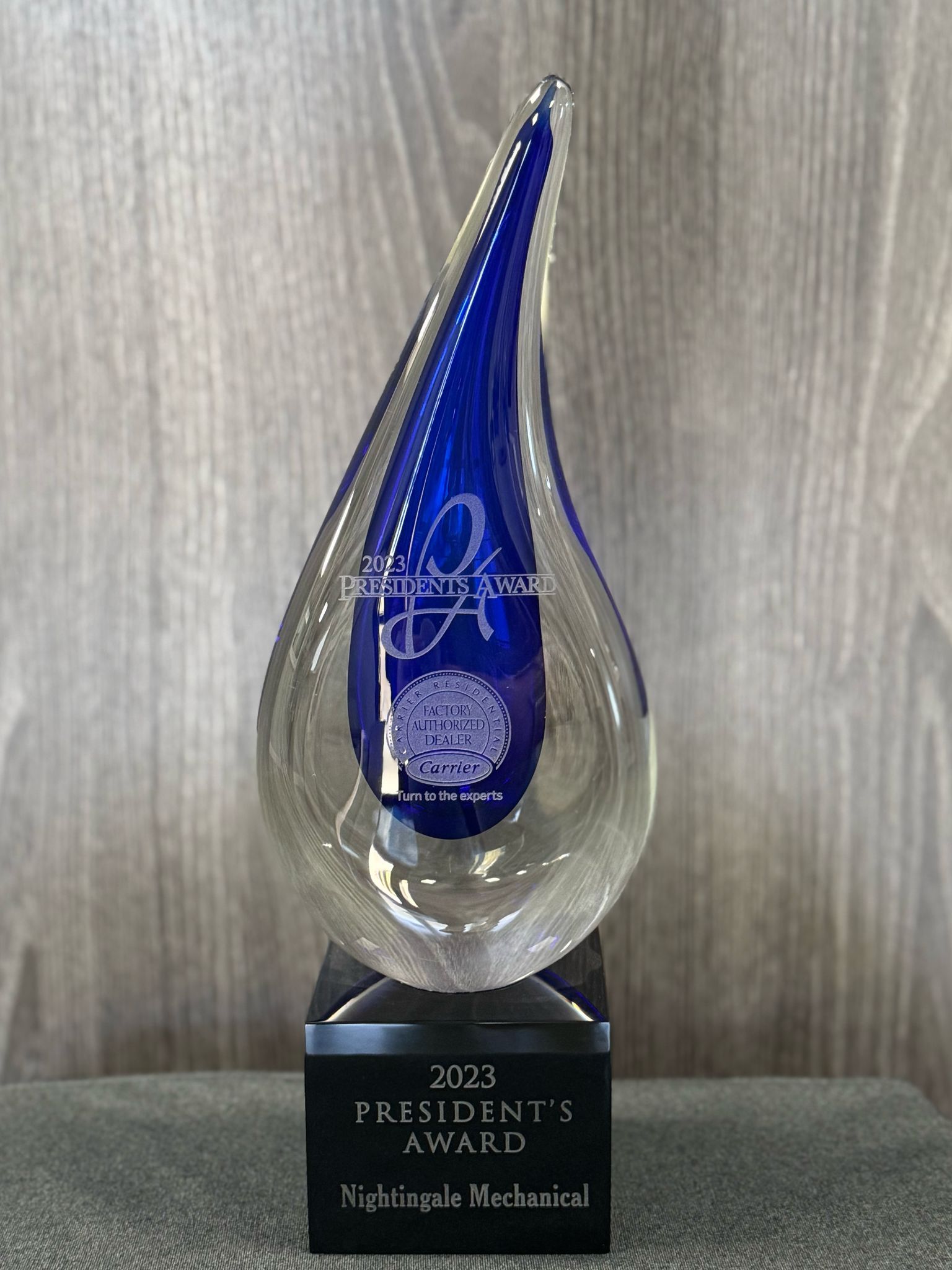 A blue glass trophy is sitting on top of a wooden table.