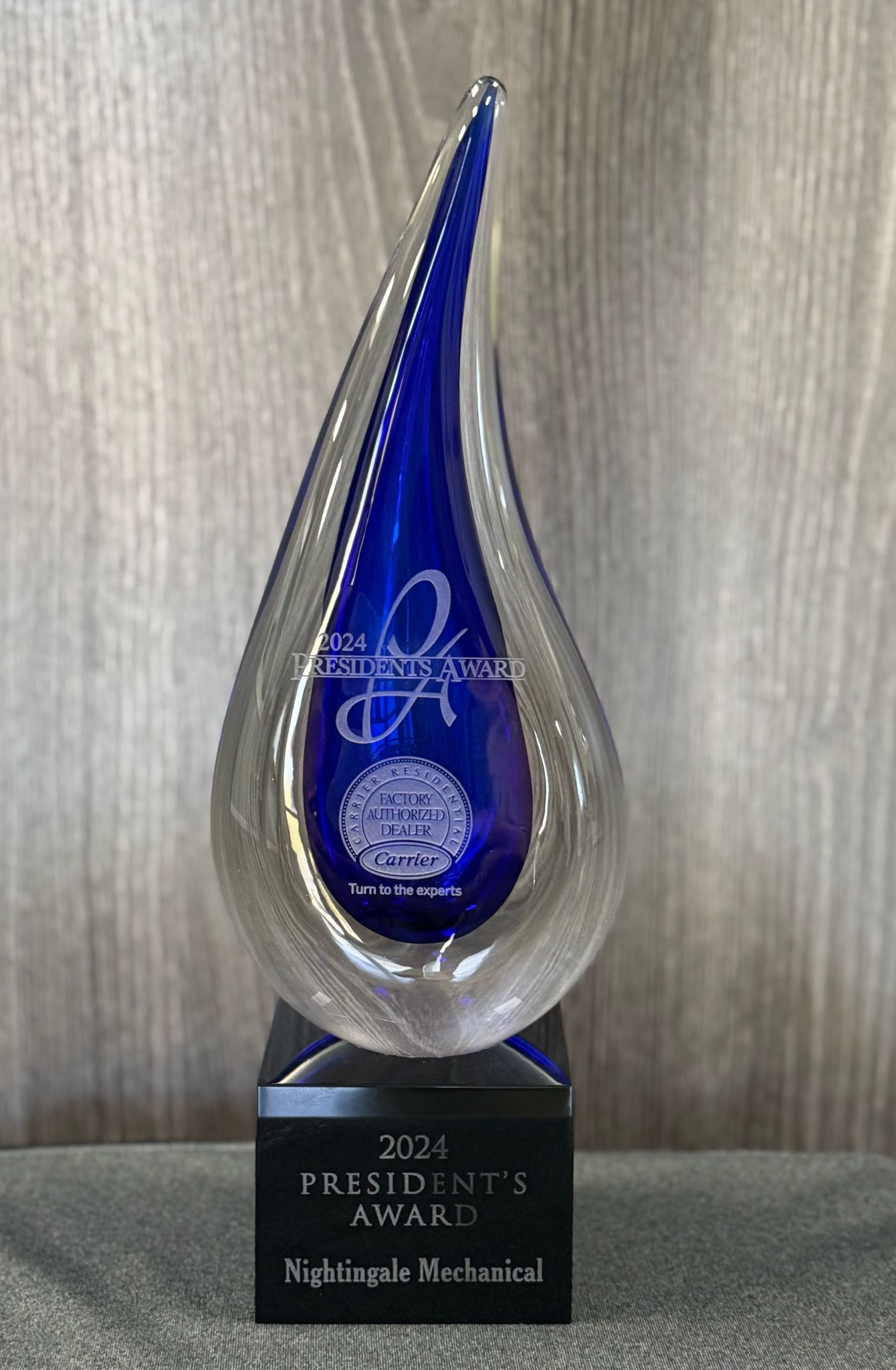 A blue glass trophy is sitting on top of a wooden table.