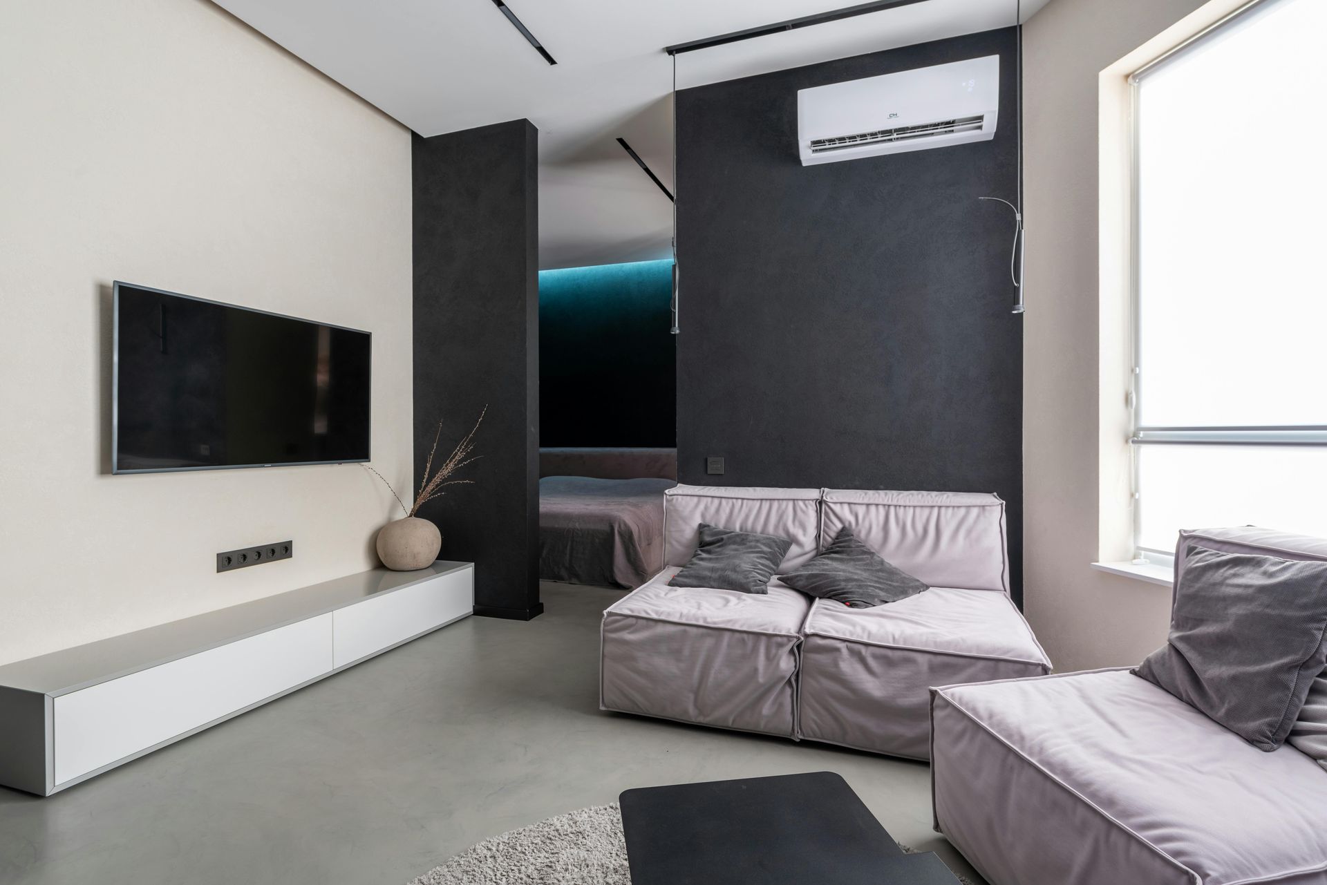 A living room with a couch , television , and air conditioner.