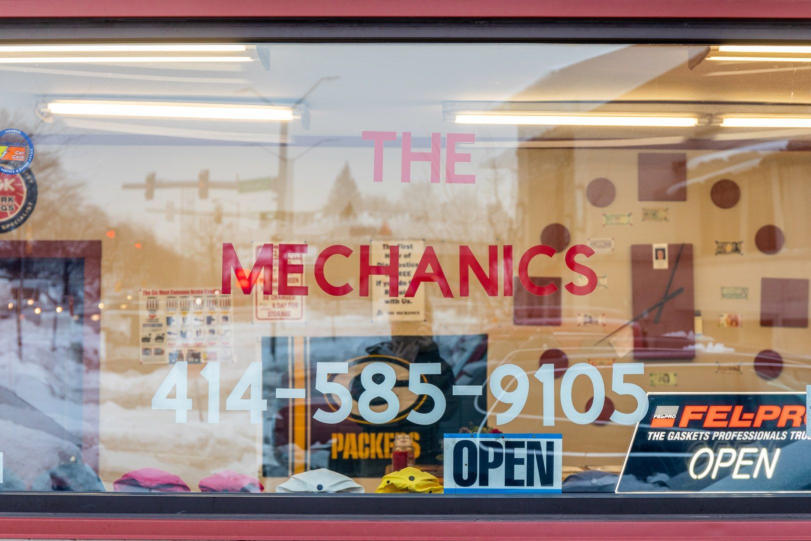 Storefront window for “The Mechanics” with phone number and open signs.