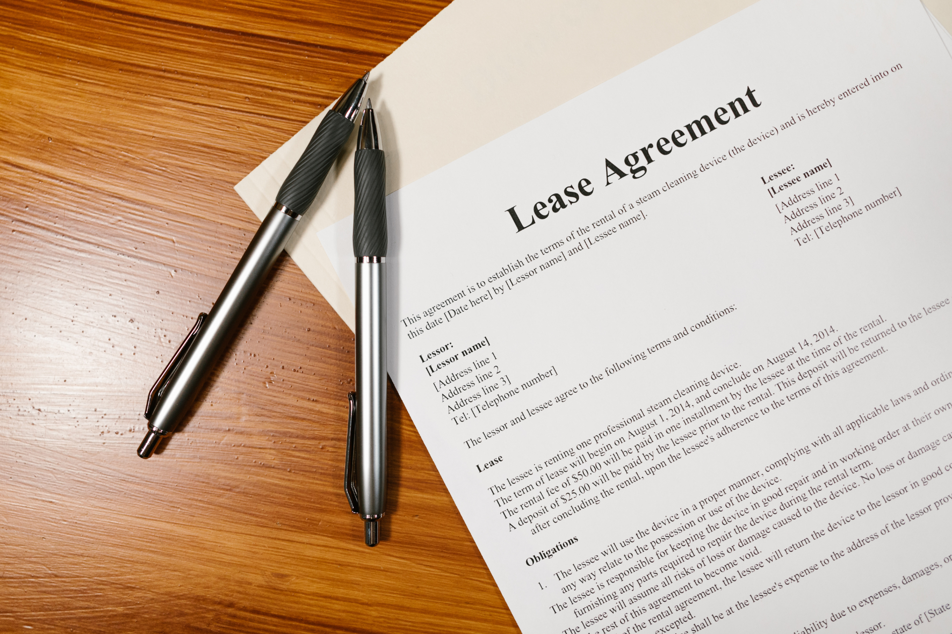 Lease agreement on a wooden desk with two pens nearby.