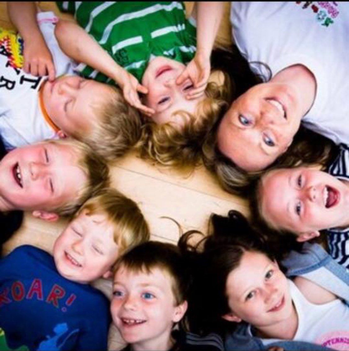A group of children are laying in a circle with one boy wearing a shirt that says roar