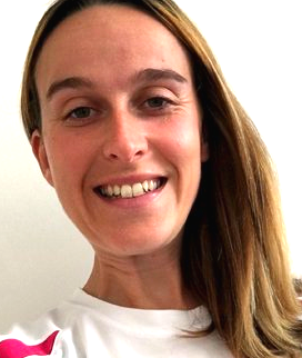 A woman is smiling and wearing a white shirt