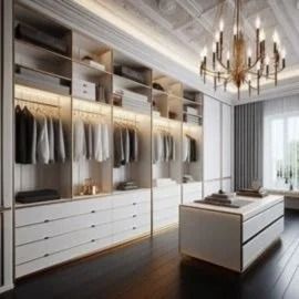 Luxurious walk-in closet with white cabinetry, hanging clothes, island, and chandelier near a window